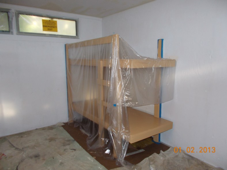 Painted bunk covered while walls get fresh coat of paint in St. Cecilia cabin in Fircrest Unit.