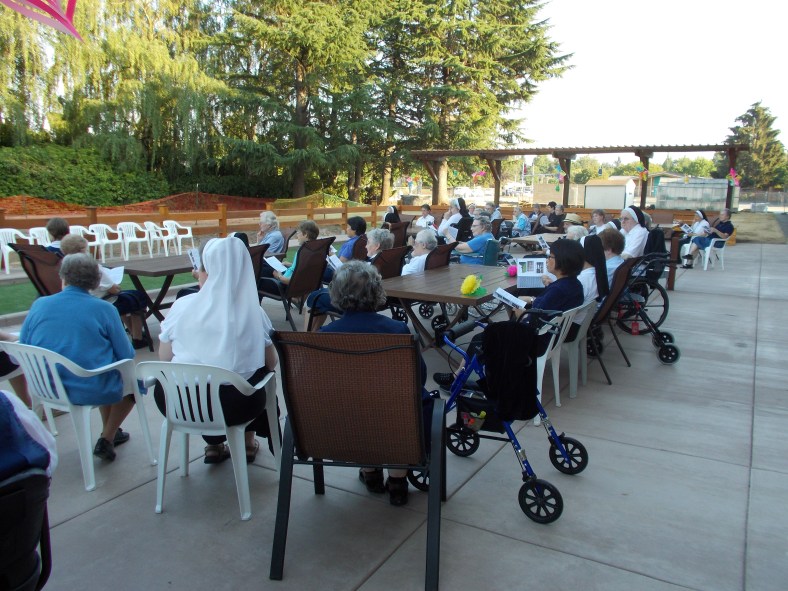 Sisters enjoy the chairs, tables and environment as they engage in the dedication service for the dedication of the new patio and bocce court.