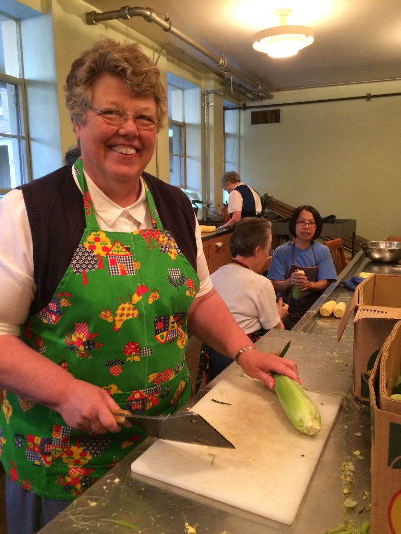 Sister Charlene cuts the ends off the ear of corn!  Look out folks! That's a big cleaver!